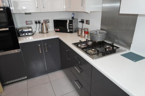 a kitchen with a stove and a microwave at Rylance Luxury House - Free Parking in Manchester