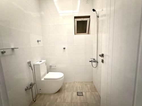 a white bathroom with a toilet and a shower at يملا Yamla in Al Madinah
