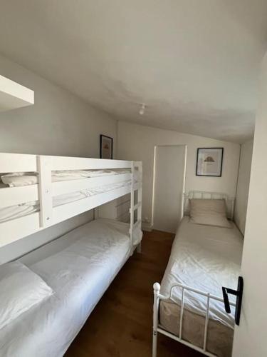 Ce lit se trouve dans un dortoir doté de 2 lits superposés et de murs blancs. dans l'établissement Maison à 200m de la plage et au cœur de la station, à Lacanau