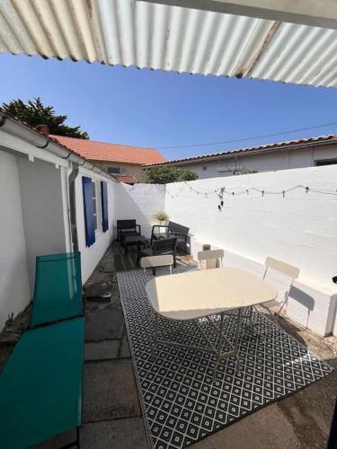 une table blanche et des chaises assises sur une terrasse dans l'établissement Maison à 200m de la plage et au cœur de la station, à Lacanau