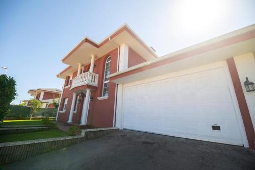 a red house with a white garage door at Chalet grande en Soto de la Marina in Liencres