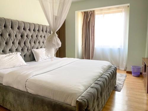 a large bed in a bedroom with a large window at Vesta H07 3Br in Nairobi
