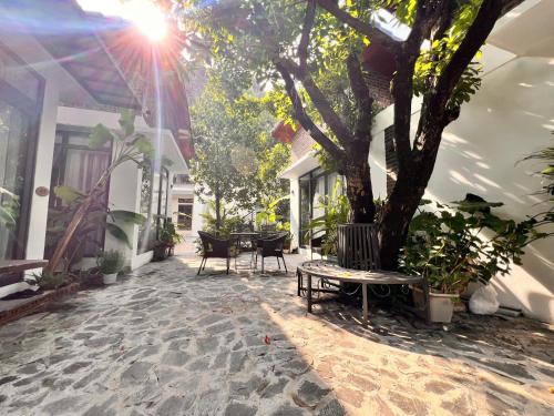 a patio with a tree and a table and chairs at Tam Coc Boutique Garden in Ninh Binh