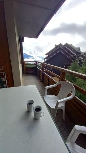d'une table blanche et d'une chaise sur un balcon. dans l'établissement T2 cosy montagne & piscine, à Puy-Saint-Vincent