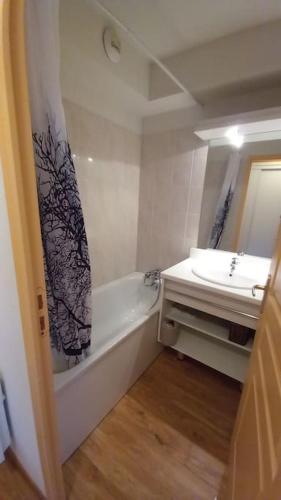 une salle de bain avec une baignoire, un lavabo et un miroir dans l'établissement T2 cosy montagne & piscine, à Puy-Saint-Vincent