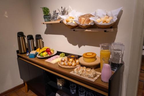 a table with food and drinks and baskets of bread at Bixiga Hostel in Sao Paulo