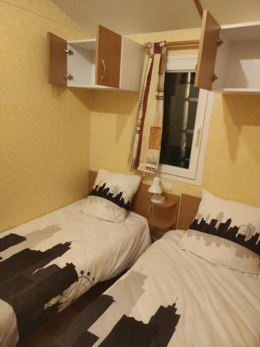 Un dormitorio con dos camas y una ventana. en Mobil home agreable et fonctionnel, en Besse-et-Saint-Anastaise