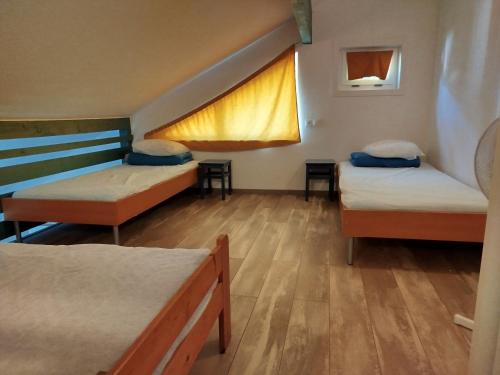 une chambre avec trois lits et une fenêtre dans l'établissement Appart'Hôtel Les ACACIAS courte et longue durée, à Bischoffsheim