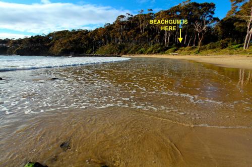 a beach with a sign that reads bathrooms here at Beachgum in Sunshine Bay