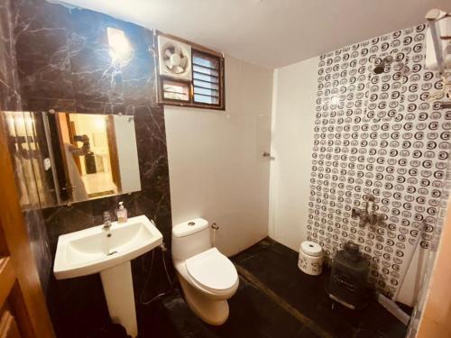 a bathroom with a white toilet and a sink at AL-MANAL 306 Premium Room Triple Bed in Bhatkal