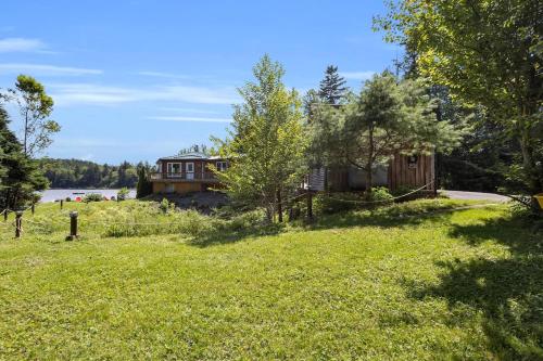 a house on a hill next to a field of grass at Cosy Lake Paradise 4-Bed Retreat Pet Friendly in Rothesay