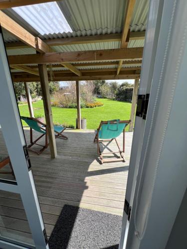 a patio with a table and chairs on a deck at @Taradise-Opunake - eco-friendly Coastal hideaway in Opunake