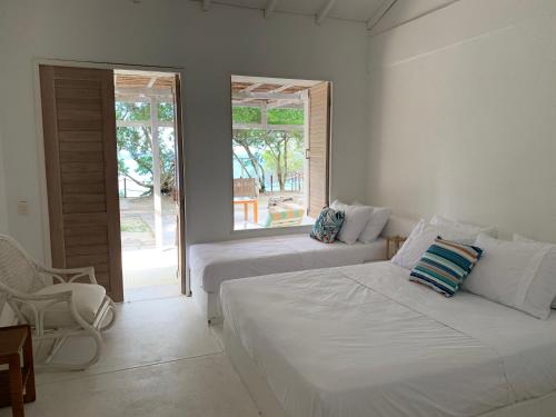 a white bedroom with two beds and a window at Casa Rosario in Isla Grande