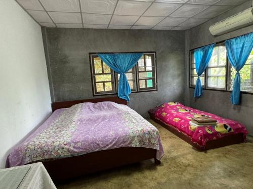 a bedroom with a bed and two windows at บ้านสวนแม่แพร-Baan Suan Mae Pair in Mae Taeng
