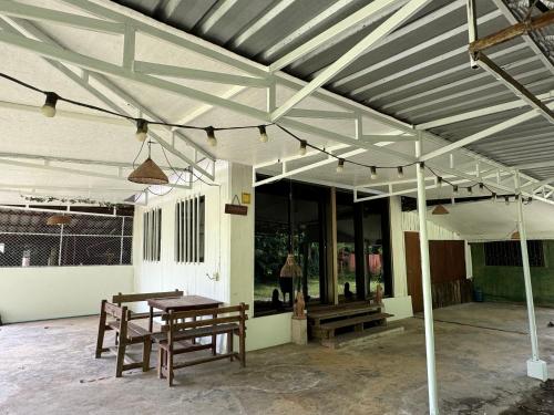 a patio with two benches and a wooden table at บ้านสวนแม่แพร-Baan Suan Mae Pair in Mae Taeng