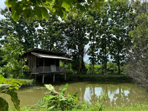 a small house next to a body of water at บ้านสวนแม่แพร-Baan Suan Mae Pair in Mae Taeng
