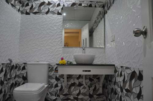 a bathroom with a toilet and a sink and a mirror at Daffodils Spice Court in Cochin