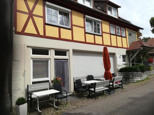 un edificio con mesas, sillas y sombrilla en Gästehaus Jagsttalblick, en Langenburg