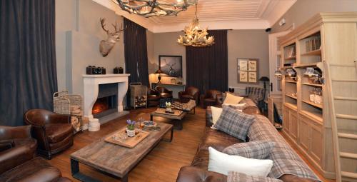 a living room with leather furniture and a fireplace at Chateau Beausaint in La-Roche-en-Ardenne