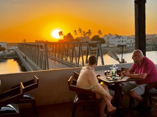 two people sitting at a table with the sunset in the background at Fly Fishes Hotel in Saint-Louis
