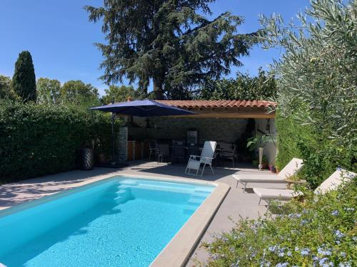 une piscine dans une cour avec un parasol dans l'établissement Maison Le Coin Joli, à Istres