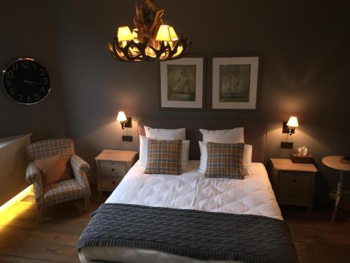 a bedroom with a bed and a clock and a chandelier at Chateau Beausaint in La-Roche-en-Ardenne