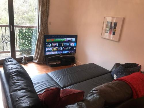 a living room with a couch and a flat screen tv at The Pentland Apartment in Penicuik