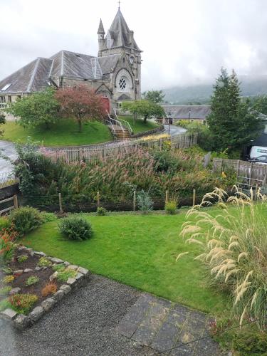 a church with a clock tower in front of a yard at Esk Cottage in Pitlochry
