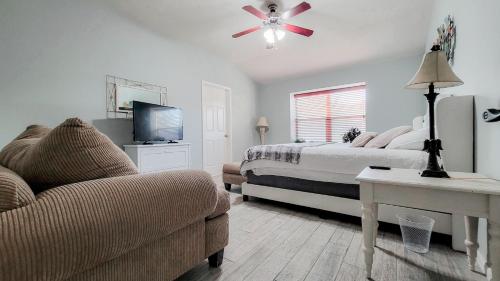 a bedroom with a bed and a couch and a tv at Springwood Executive Home near Exxon Campus in Spring