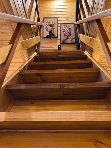 a staircase in a wooden house with two pictures at Chalés Laraland in Campos do Jordão