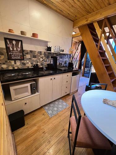 a kitchen with a counter and a table in a room at Chalés Laraland in Campos do Jordão