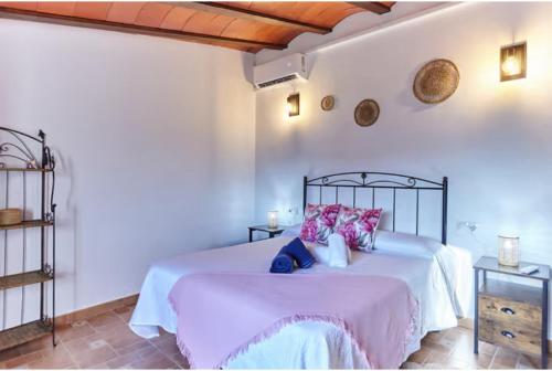 a bedroom with a large white bed with pink pillows at Alojamiento turístico Loma Alta in Cambil