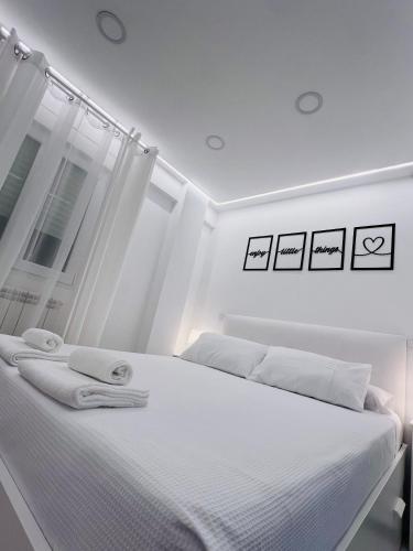 a white bedroom with a bed with towels on it at Golden Apartment in Santander