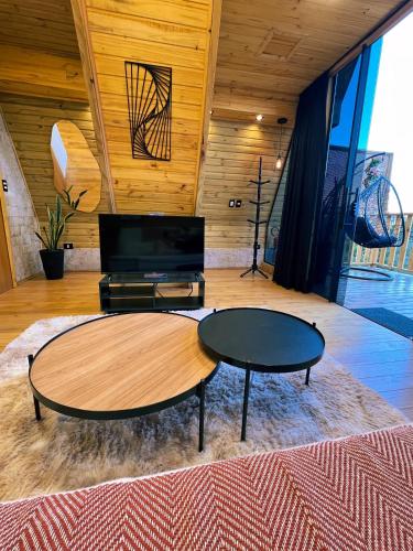 a living room with a table and a tv at Chalés Laraland in Campos do Jordão