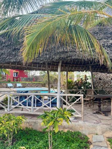 a pavilion with a table and a palm tree at Manasha Watamu in Watamu