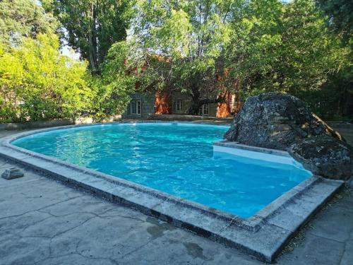 a large blue pool with a rock in the middle at Casa rural chimenea y barbacoa in Escorial