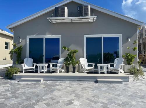 a patio with white chairs and tables and windows at Sunset Hideaway in West Bay