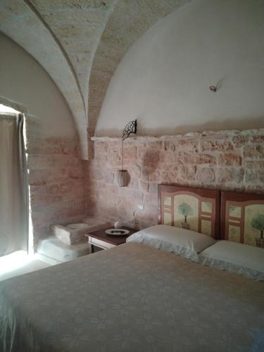 a bedroom with a bed and a stone wall at Trullo Amedee in Ostuni