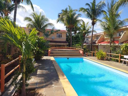 a swimming pool with palm trees in front of a building at 3-Bedroom Duplex, Residence Bayview, Flic-en-Flac in Flic-en-Flac