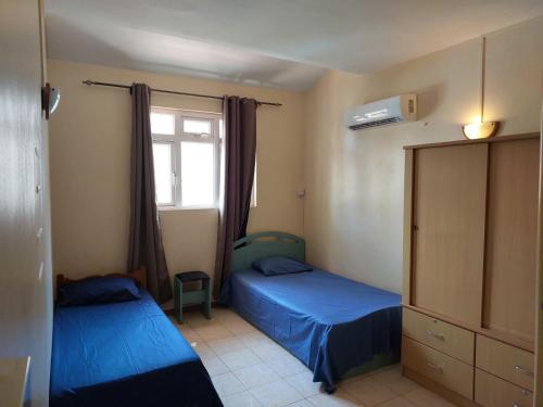 a bedroom with two beds and a window at 3-Bedroom Duplex, Residence Bayview, Flic-en-Flac in Flic-en-Flac