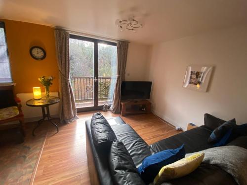 a living room with a couch and a balcony at The Pentland Apartment in Penicuik