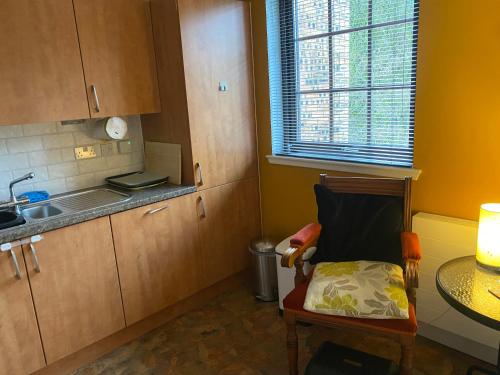 a kitchen with a chair and a table and a sink at The Pentland Apartment in Penicuik