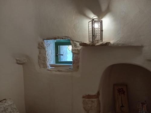 a room with a window and a lamp on a wall at Trullo Amedee in Ostuni
