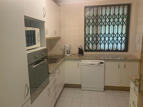 a kitchen with white cabinets and a dishwasher at Moradia 3 quartos com piscina partilhada no Gerês Caniçada Braga in Vieira do Minho