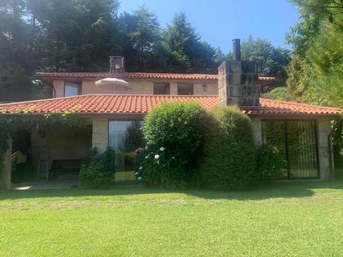 a house with a fence and bushes in the yard at Moradia 3 quartos com piscina partilhada no Gerês Caniçada Braga in Vieira do Minho