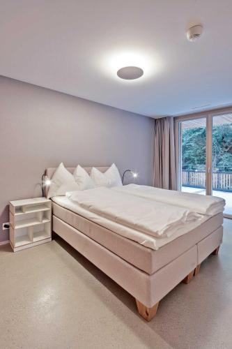 a bedroom with a large white bed with a window at VIASTENNA - Boutique Ferienwohnung in Flims