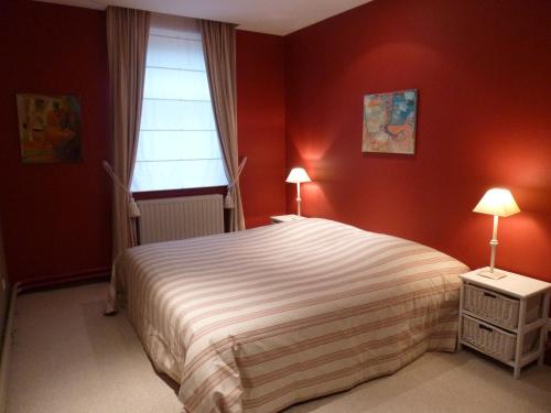 een slaapkamer met een bed met rode muren en een raam bij Maison Chantraine in Ramillies