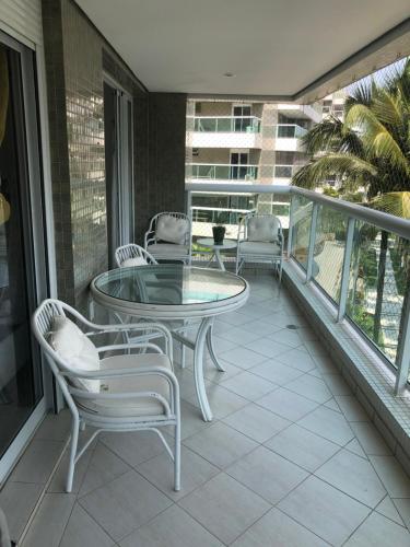 a balcony with a glass table and chairs on it at ILHA DA MADEIRA Resort apto inteiro in Riviera de São Lourenço