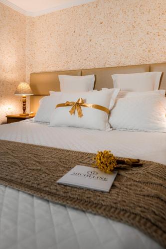a bed with white pillows with a welcome card on it at Micheline Hotel Tricot - ao lado da Rua Coberta in Gramado