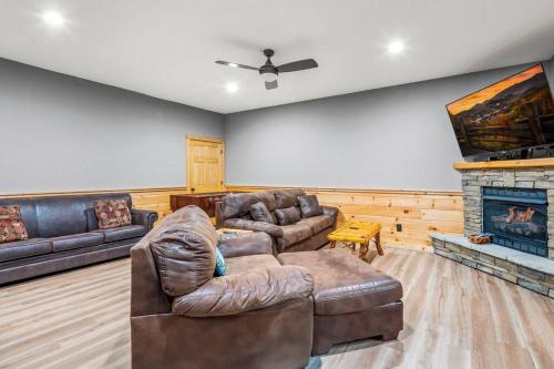 a living room with a leather couch and a fireplace at Relax, Play & Enjoy Mountain Views and Hot Tub in Pittman Center